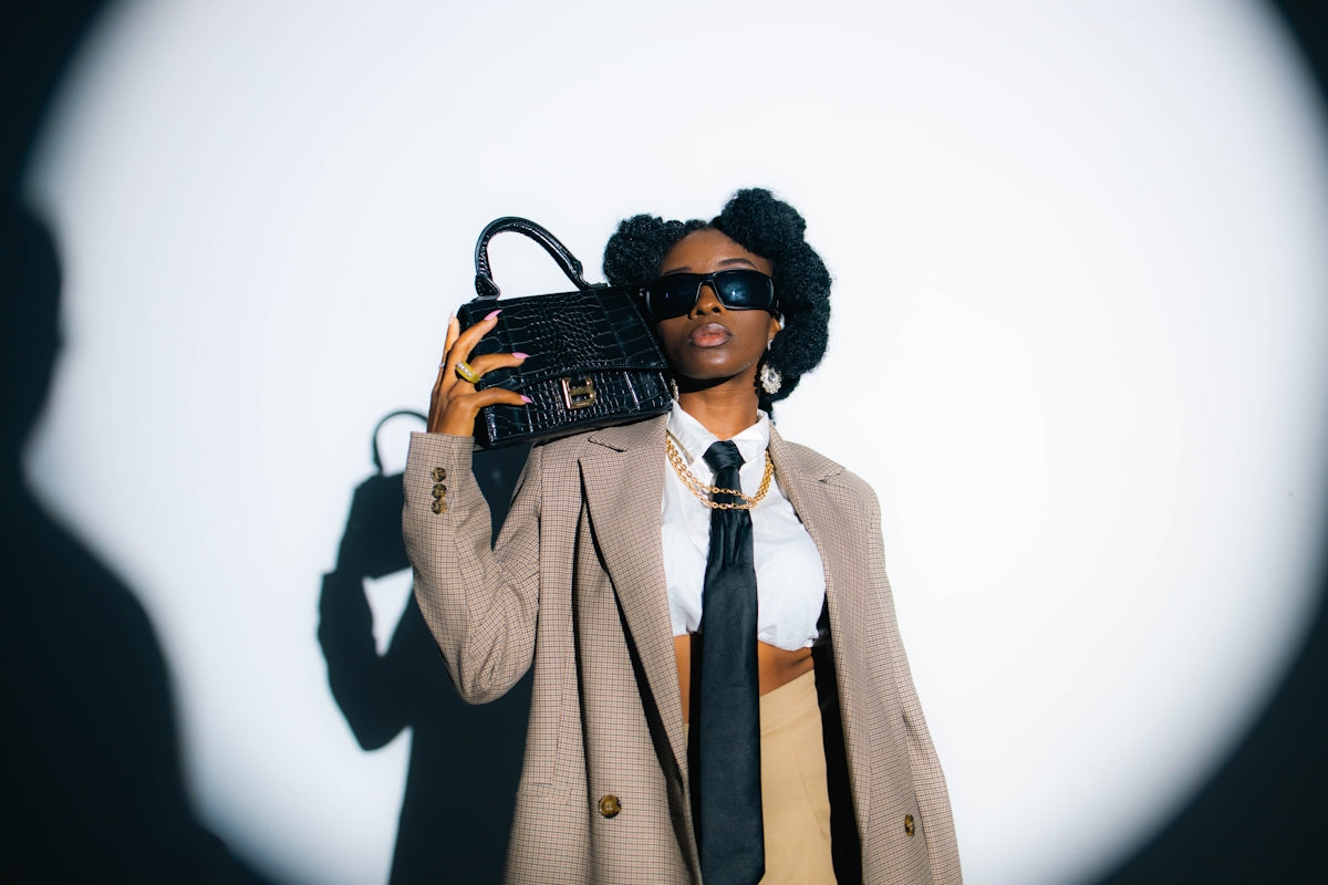 A woman in a coat and tie holding a purse