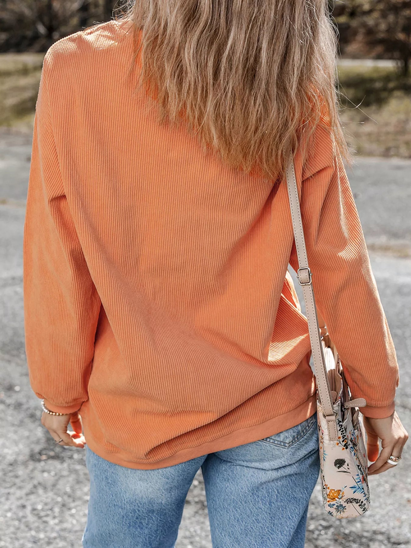 Orange corduroy long sleeve top with floral bag, styled with blue jeans for casual women's fashion