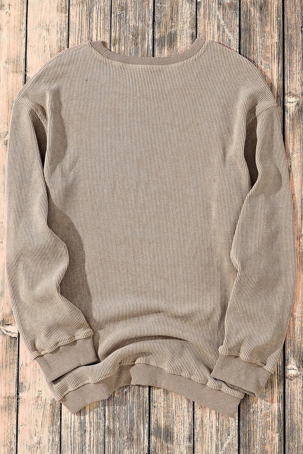 Beige ribbed long sleeve sweatshirt laid flat on rustic wood, cozy casual top for women
