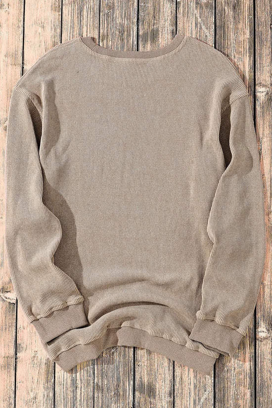 Beige ribbed long sleeve sweatshirt laid flat on rustic wood, cozy casual top for women