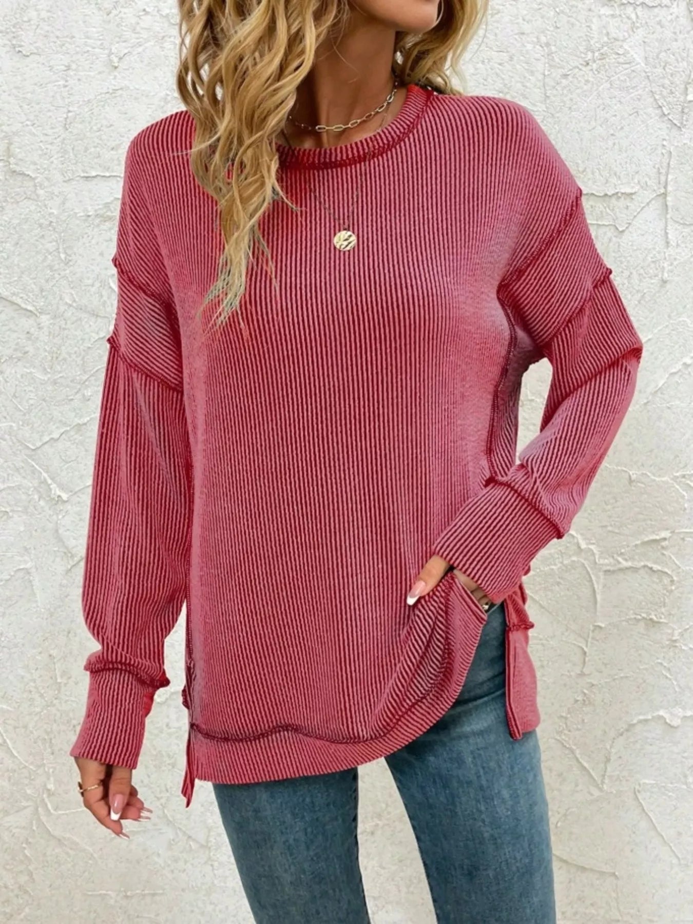 Pink ribbed long sleeve top with side slits, paired with jeans for casual women's fashion