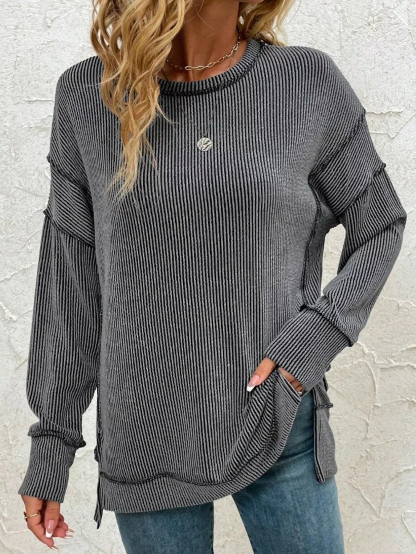 Gray ribbed long sleeve top with side slits, paired with jeans for casual women's fashion