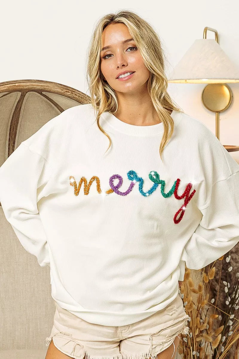 White cozy sweatshirt with colorful 'merry' sequin lettering, perfect for festive women's fashion