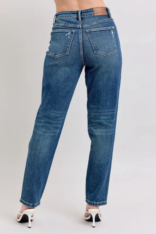 Women's high-waisted straight leg jeans with back pockets, paired with white heels