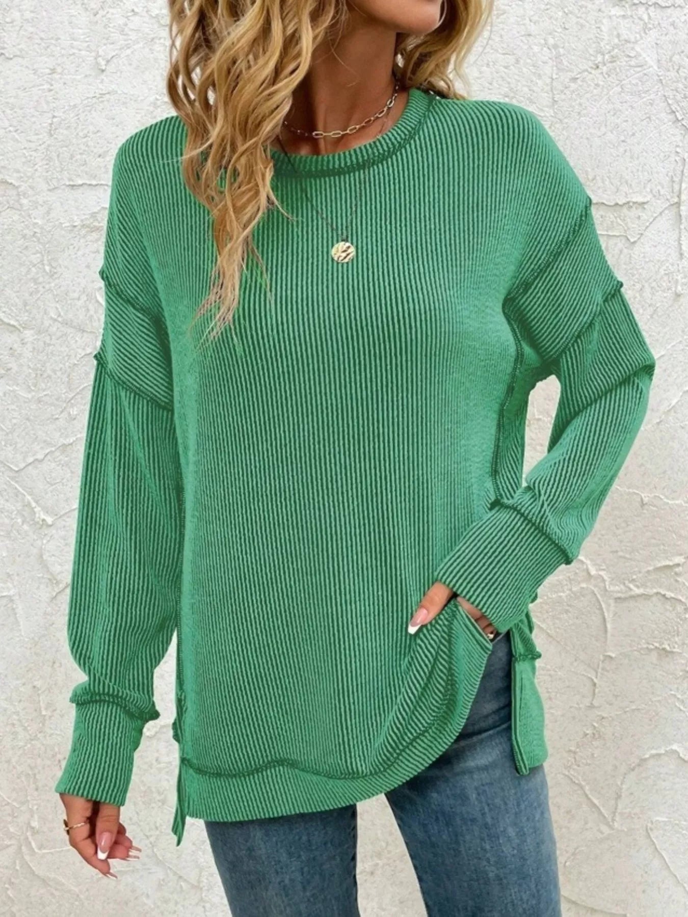 Green ribbed long sleeve top with side slits, paired with jeans for casual women's fashion